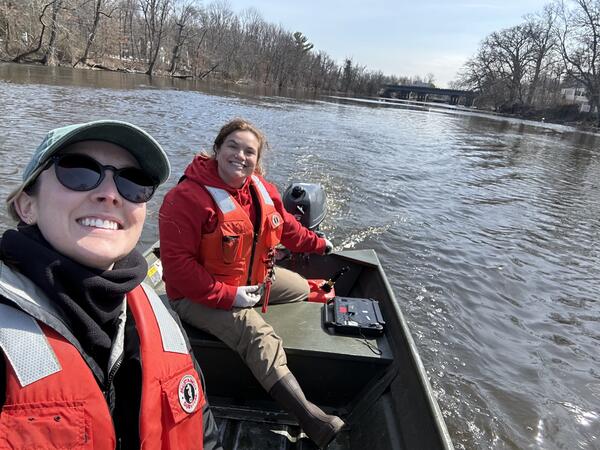 "Selfie" style shot of two scientists in a small boat sailing up the river
