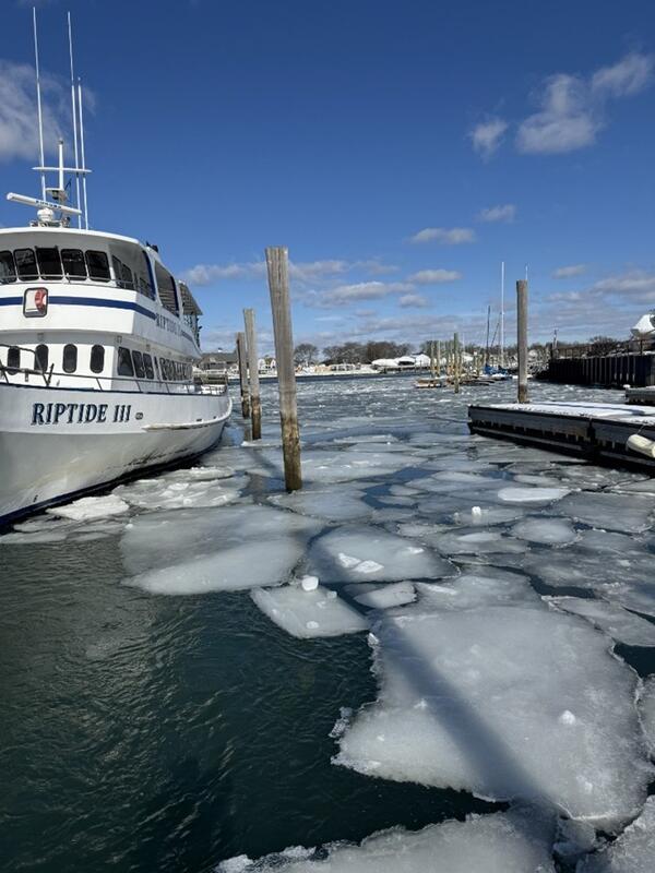Chunks of ice on top of water near a dock and boat.