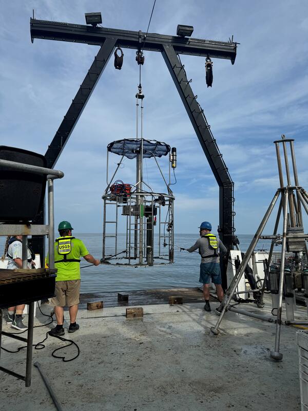 Three people on deck of ship working with mega multicorer