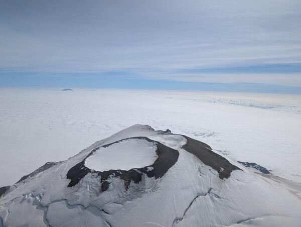 Color photos of the summit of Mount Rainier with snow on the mountain and clouds below.