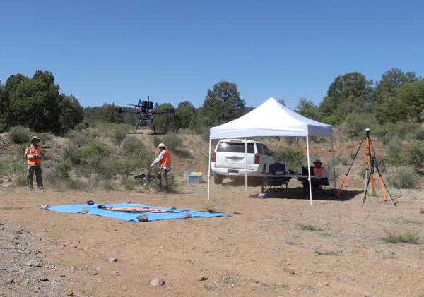 Crew operating drone by tent work station and testing equipment