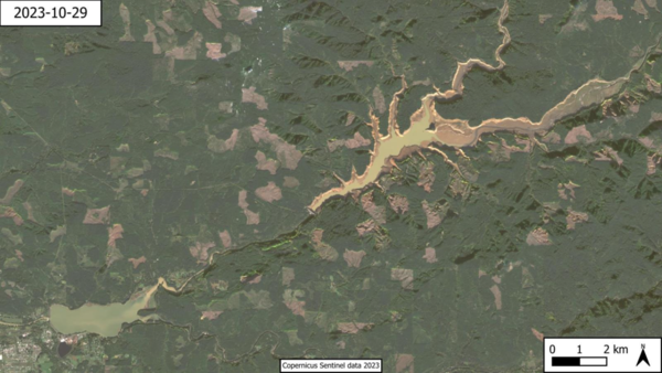 satellite image: Green forest land surrounds two reservoirs with brownish-green water 