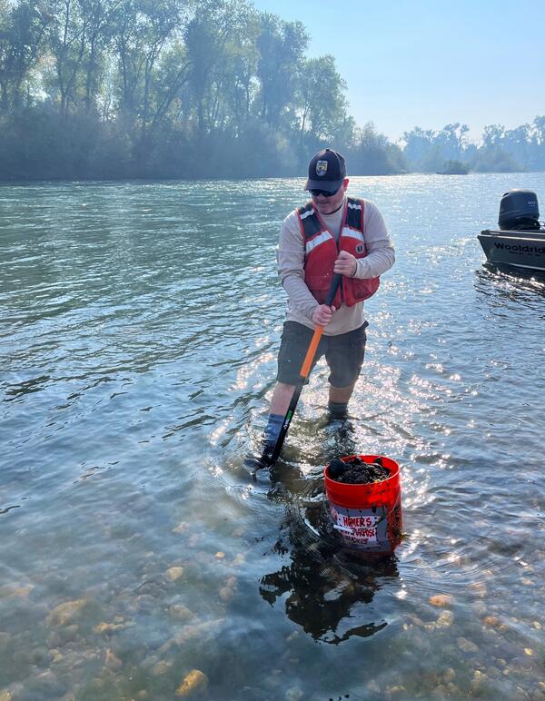 Man in stream with shovel and bucket