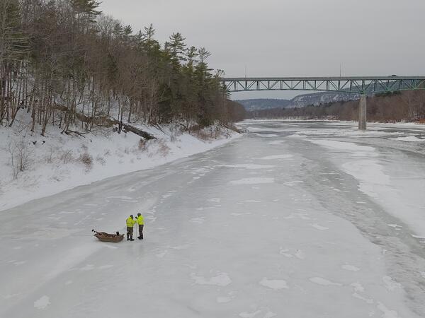 Two men standing next to an Ice Sled on the frozen Delaware River as they prepare to make a measurement