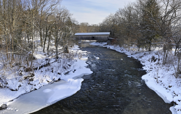 A covered bridge over a snowy river.