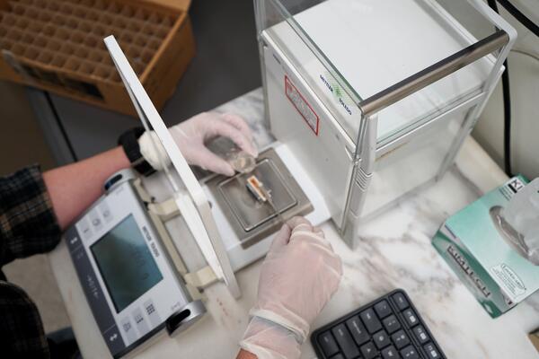 Scientist weighing sample on analytical lab balance