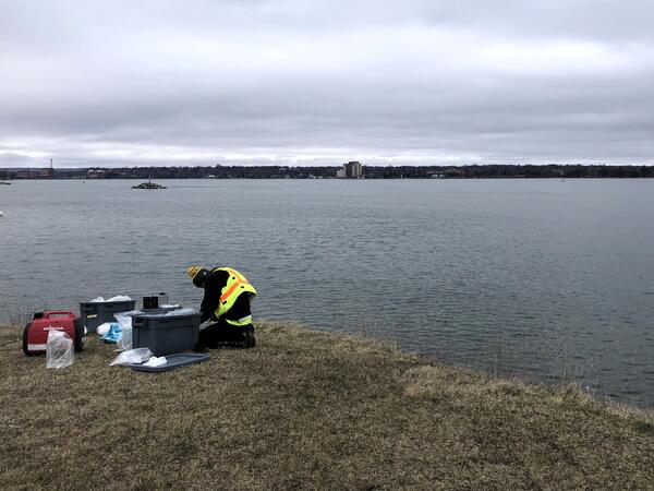 Scientist sampling water near shoreline of river on an overcast day