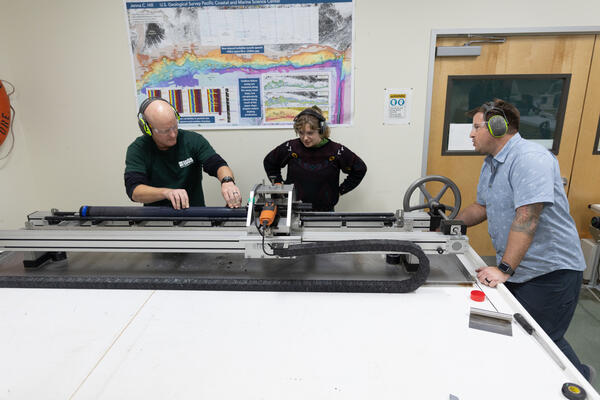 Scientists splitting a sediment core with the GeoTek core splitter