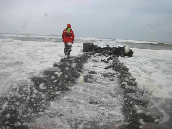 USGS scientist measuring high water marks on a jetty into the Long Island Sound during flooding.