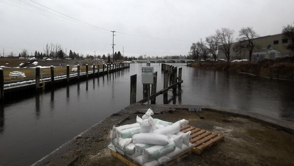 Streamgage at river with buildings on shore, sandbags in foreground