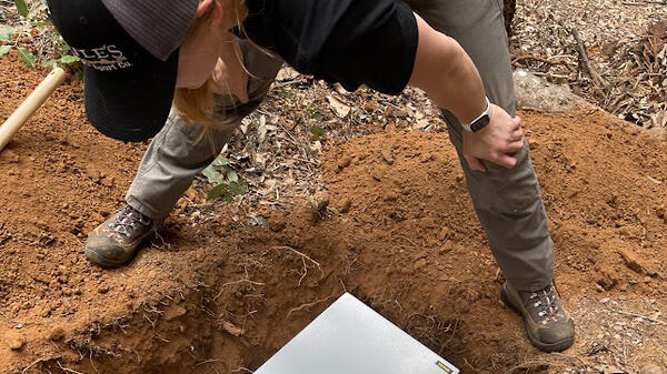 woman hunched over metal box in ground