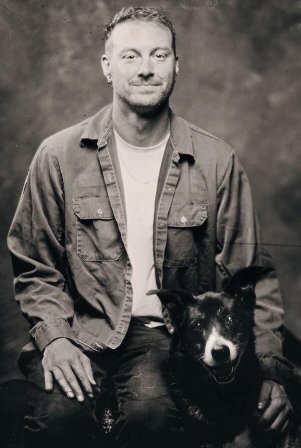 A black and white staff photo of Trevor Faske with his dog