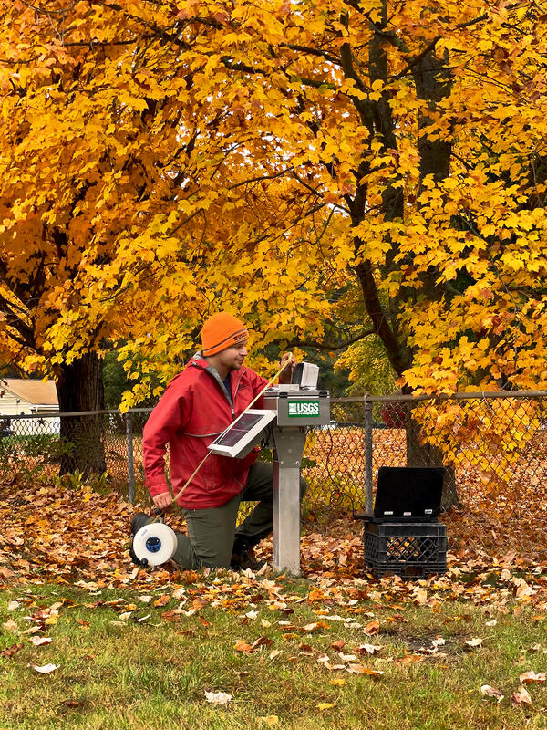 USGS scientist reads an electronic tape measure that has been lowered into a groundwater well during fall.