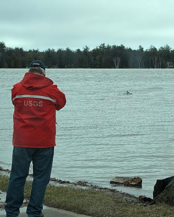 Hydrologic technician views submerged streamgage house in flooded lake