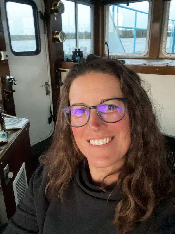 A researcher sitting on the bridge of a large vessel. Lake in the background.