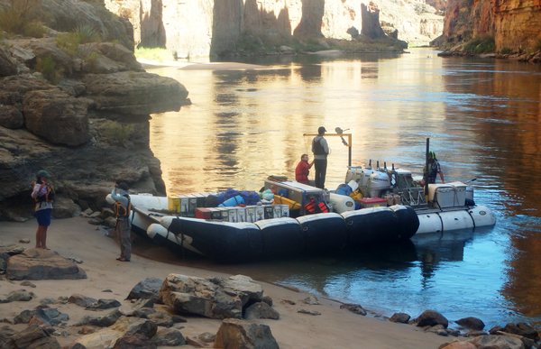 Researchers stand on a boat that's parked on a sandbar along the Colorado River in Grand Canyon