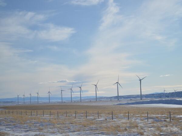 Row of wind turbines with a barb-wire fence in the foreground 