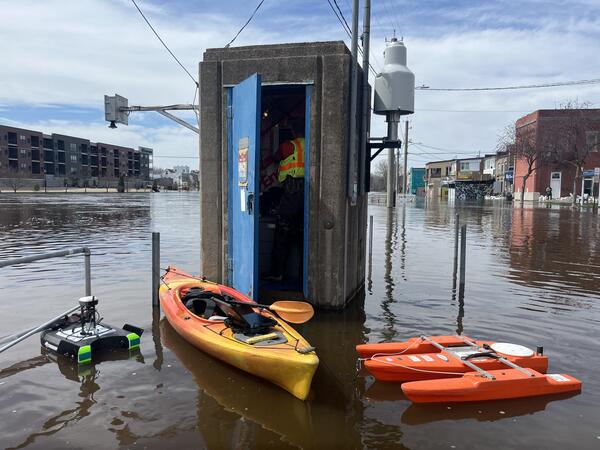 Hydrologic technician inside gage house with kayak and two ADCPs floating outside