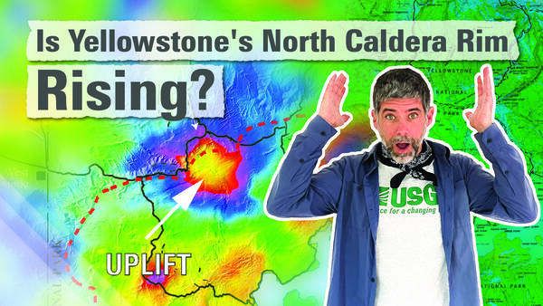 Man in blue shirt with astonished look on his face holding arms in air in front of a colorful map of Yellowstone