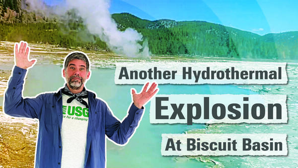 Man in blue shirt holding hands up with a blue pool and spouting geyser in the background