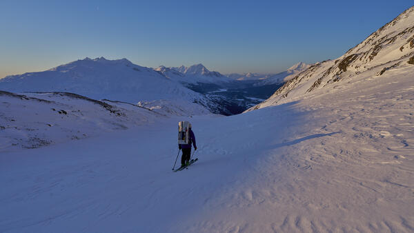 Person with a backpack skiing down a glacier.