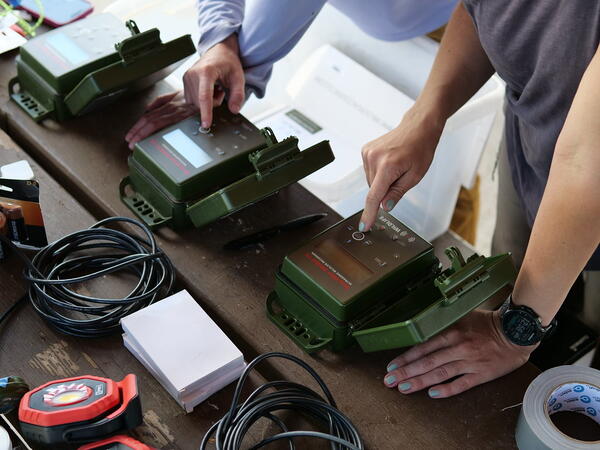 hands touch different acoustic devices on a table