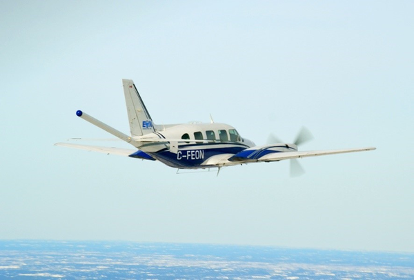 A small blue and white airplane flies in the sky