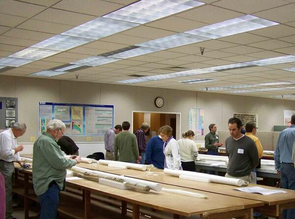 A room of people examine rock core laid out on a table