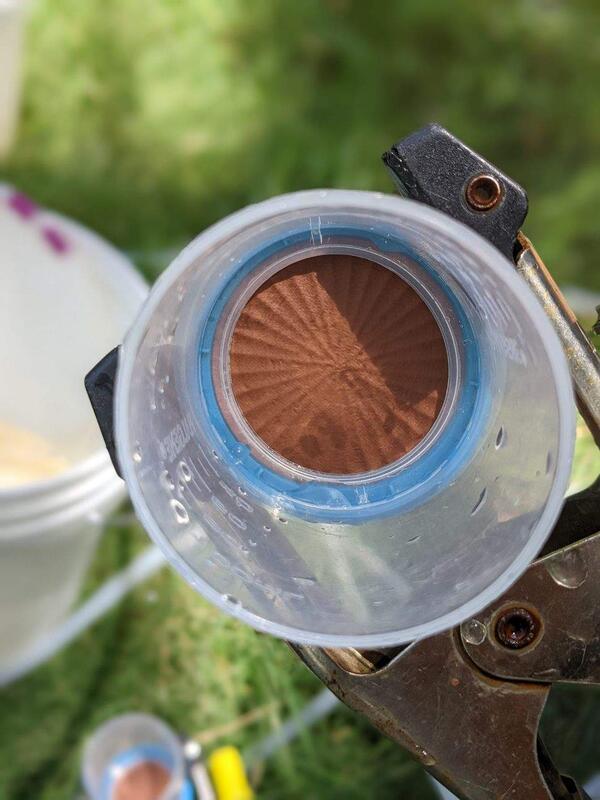 An opened eDNA filter cartridge showing the membrane with eDNA sample and red sediment