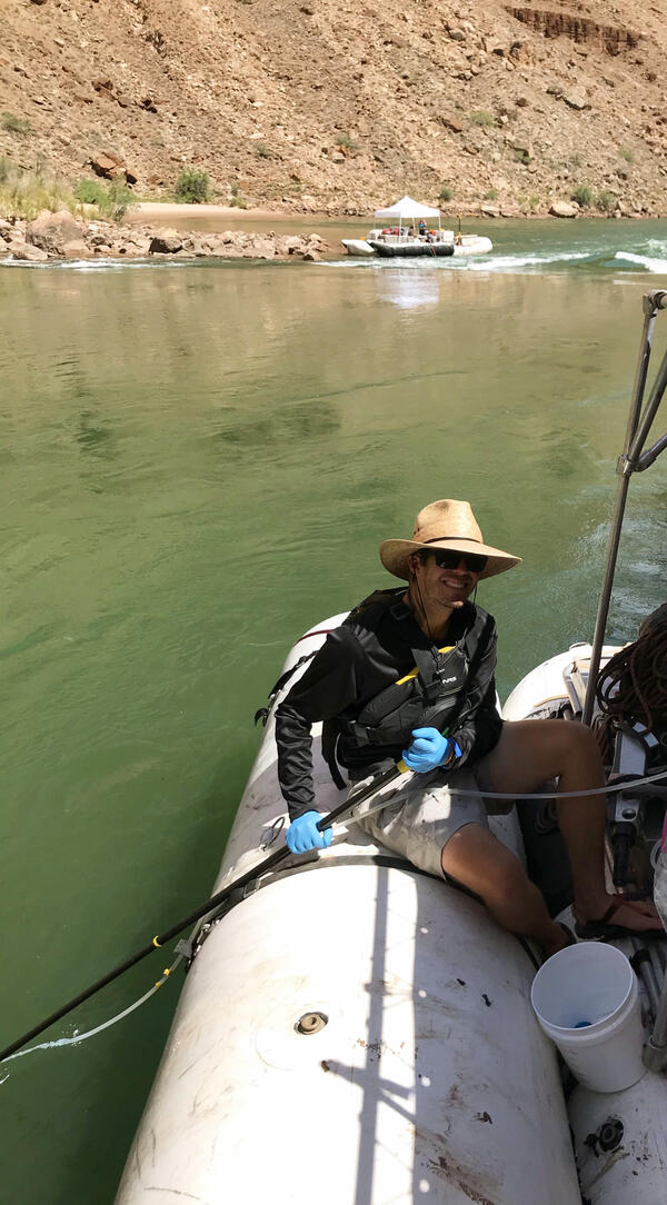 On a research boat in the Grand Canyon, a man collects samples from the Colorado River using an eDNA sampler.
