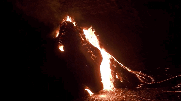 Lava bubbling out of a fissure at night time.