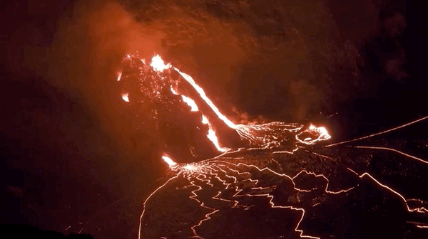 Lava bubbling out of a fissure at night time.