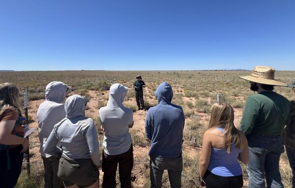 Students watch a USGS ecologist describe restoration experiments in a field in Northern Arizona rangelands
