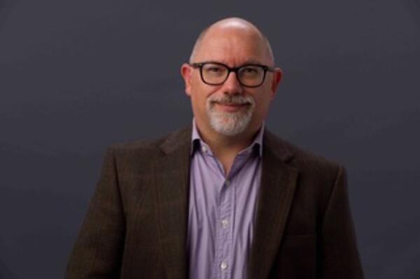 man wearing glasses, purple shirt, and brown blazer