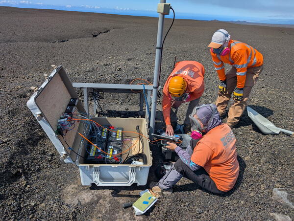 Scientists work gather around a volcano monitoring station