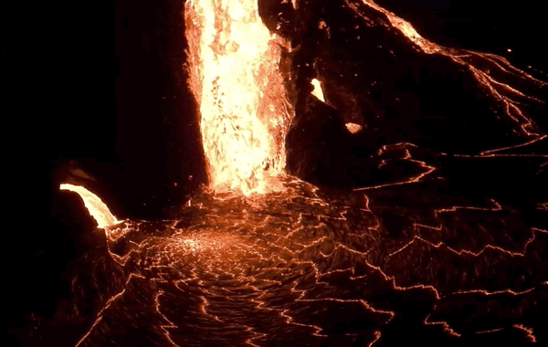 Lava flowing as a waterfall at night into a lava lake