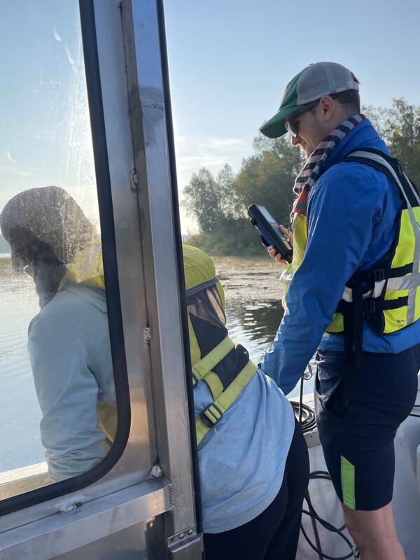Two scientists measure water quality from a boat
