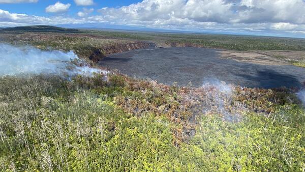 Color photograph of fire in vegetation near crater