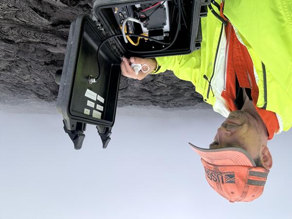 Color photograph of USGS scientist examining webcam