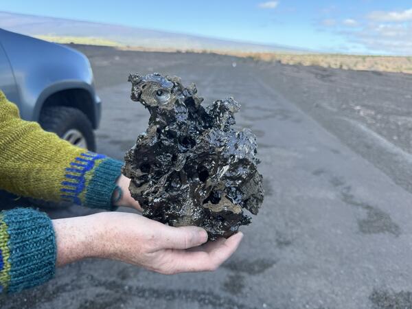 Color photograph of scientist holding a sample of lava