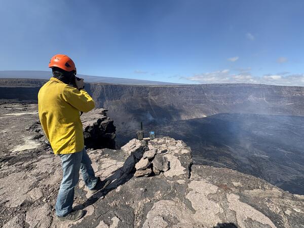 Color photograph of scientist on rim of caldera