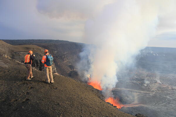 Color photograph of scientists monitoring eruption on caldera rim