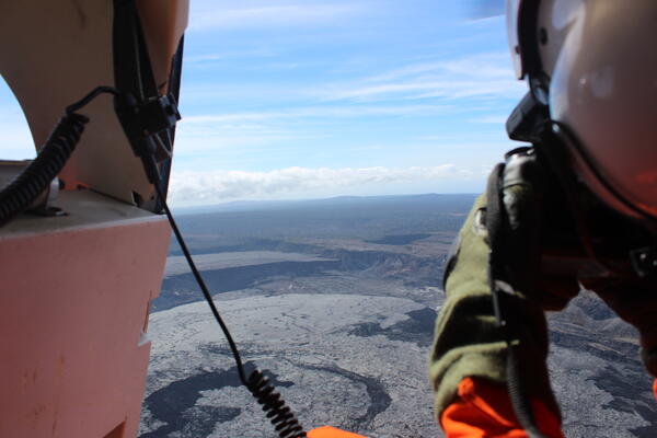 Color photograph of scientist taking photos from helicopter