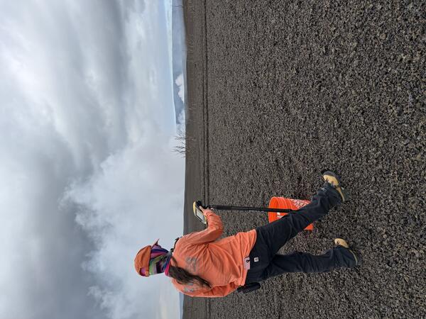 Color photograph of scientist taking measurement on volcanic landscape