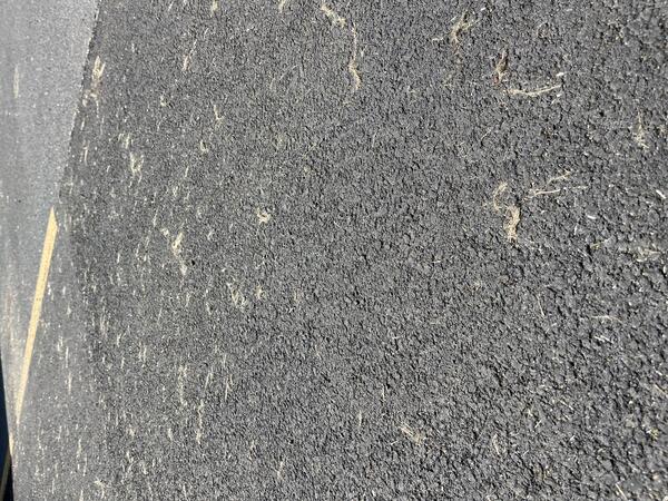 Color photograph of fine particles of volcanic glass on a paved road