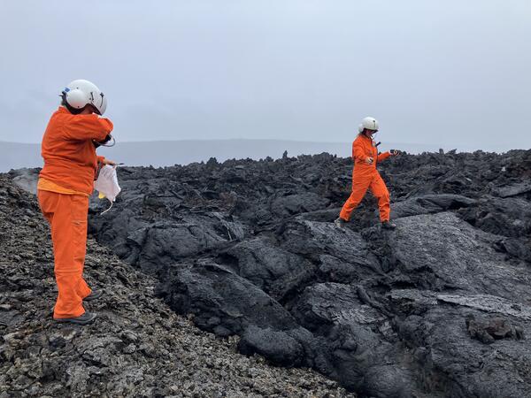 Color photograph of two scientists collecting samples from cooled lava flows