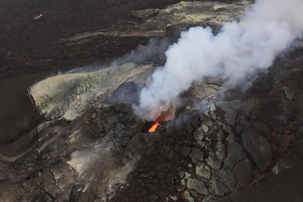 Color photograph of volcanic vent with roiling lava in it