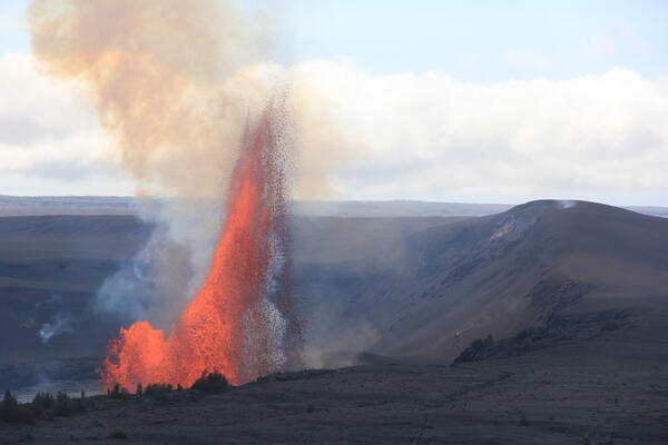 Color photograph of lava fountaining with crater rim in foreground