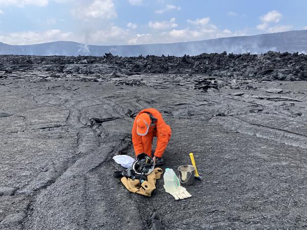 Color photograph of scientist assembling gear on lava flows located on crater floor