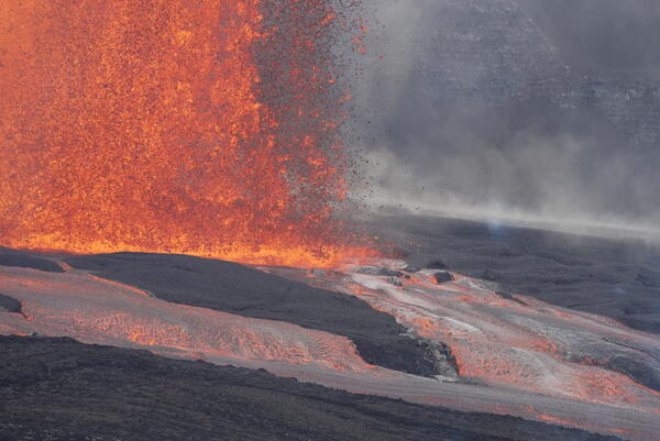 Color photograph of lava fountain base and lava flowing in channel